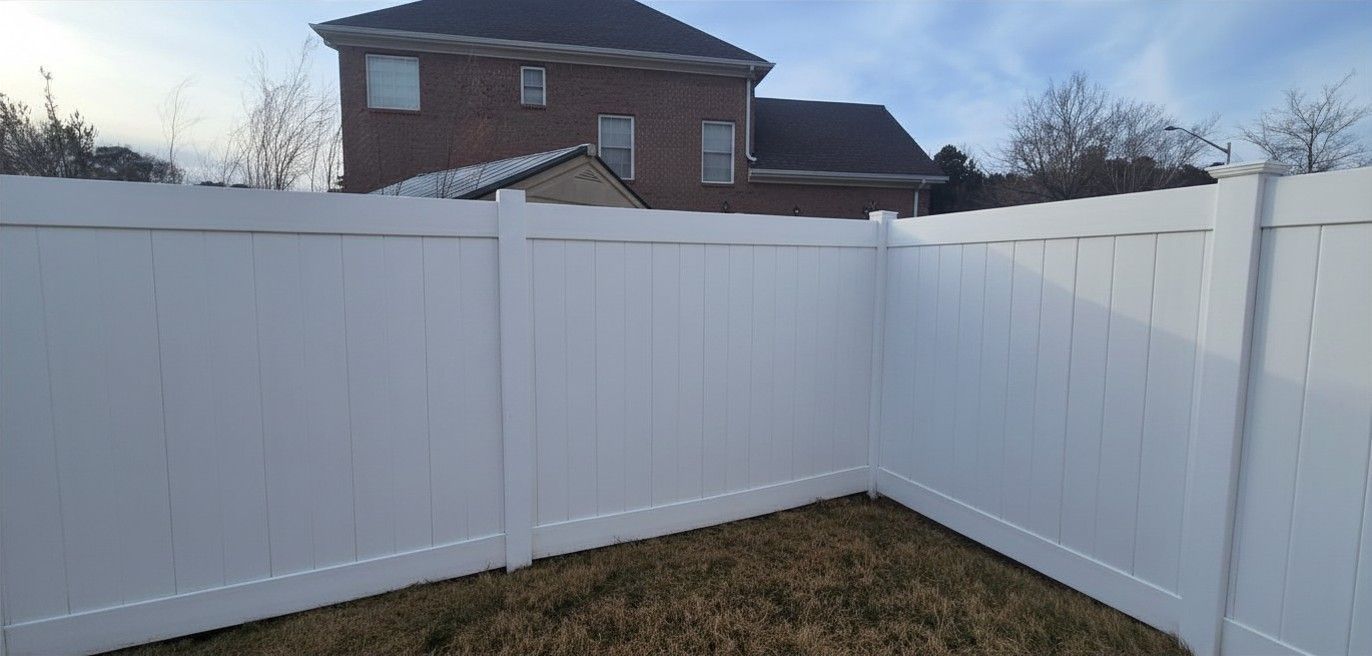 White vinyl privacy fence enclosing a yard with a house visible above it