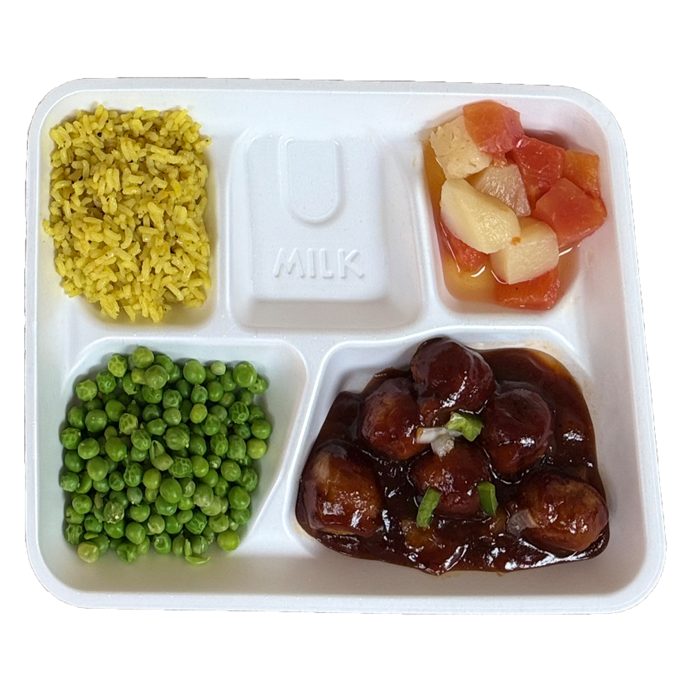 A styrofoam tray filled with meatballs , peas , rice and fruit.