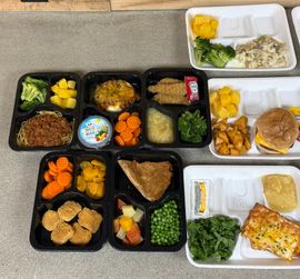 A bunch of trays of food are sitting on a table.
