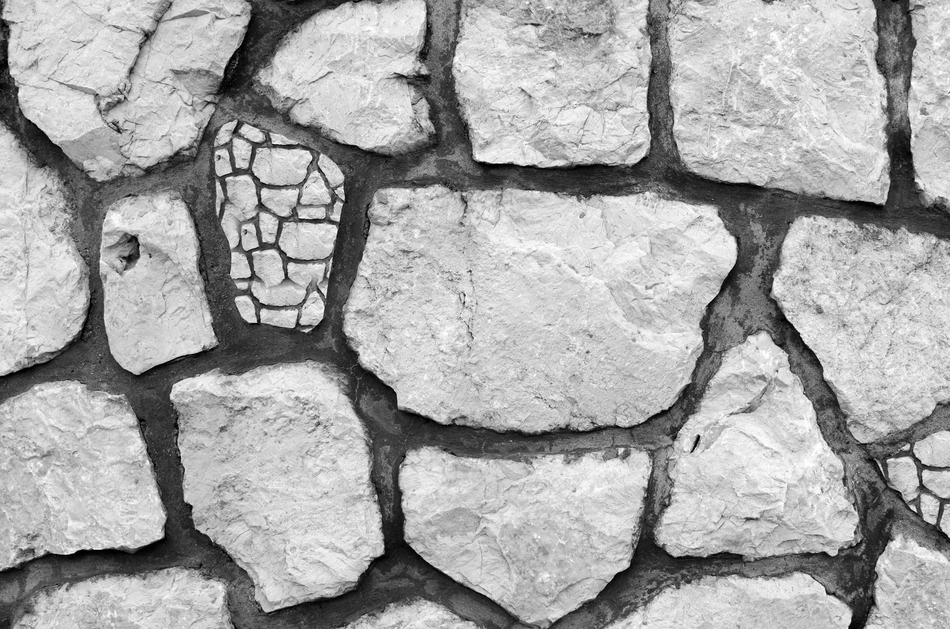Stone wall, irregularly shaped gray stones with dark gray grout.