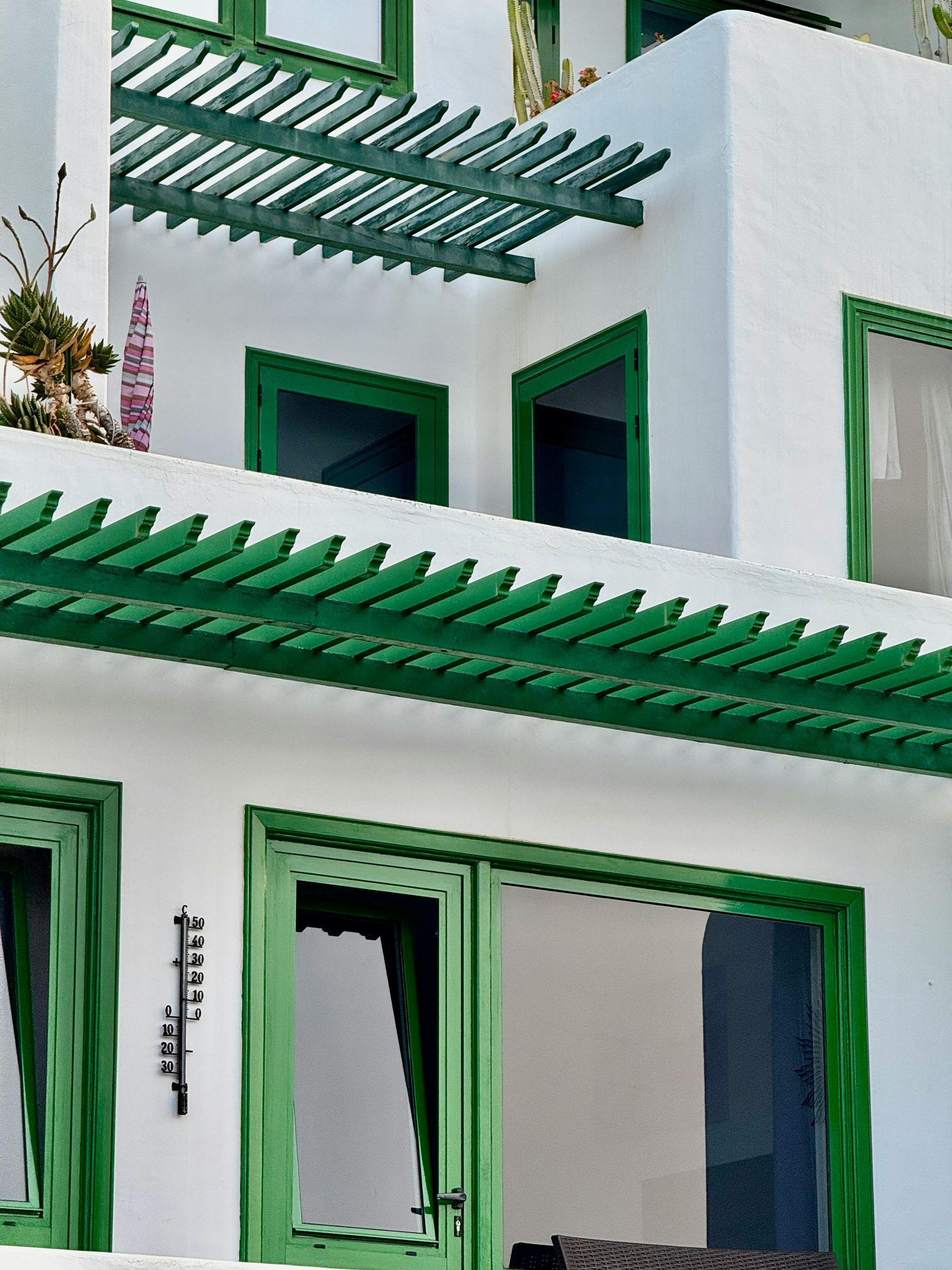 White building with green window frames and a green pergola.