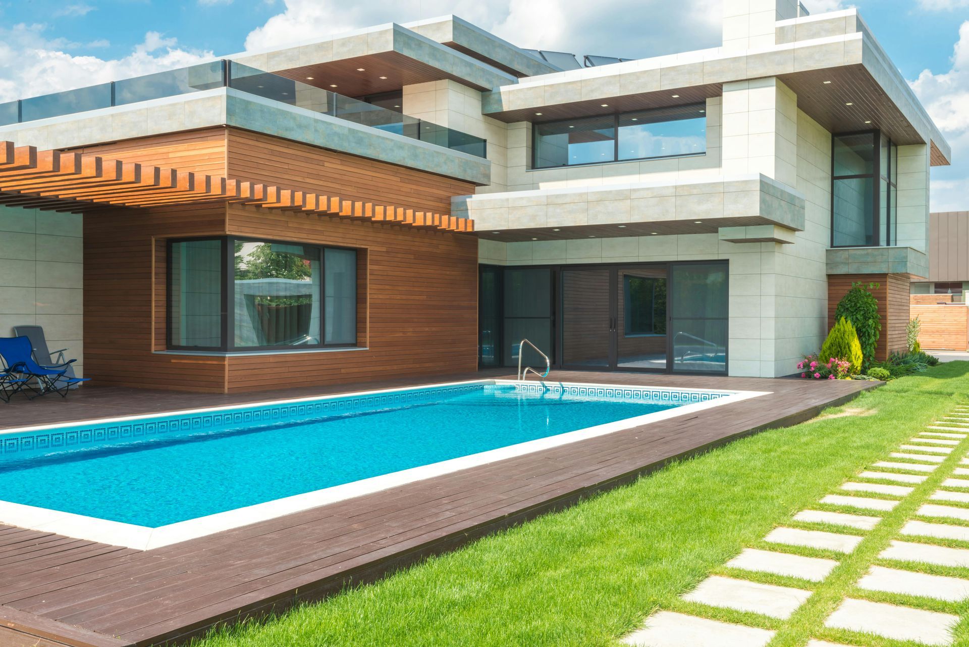 Modern house with a rectangular pool, brown wooden siding, and green lawn.