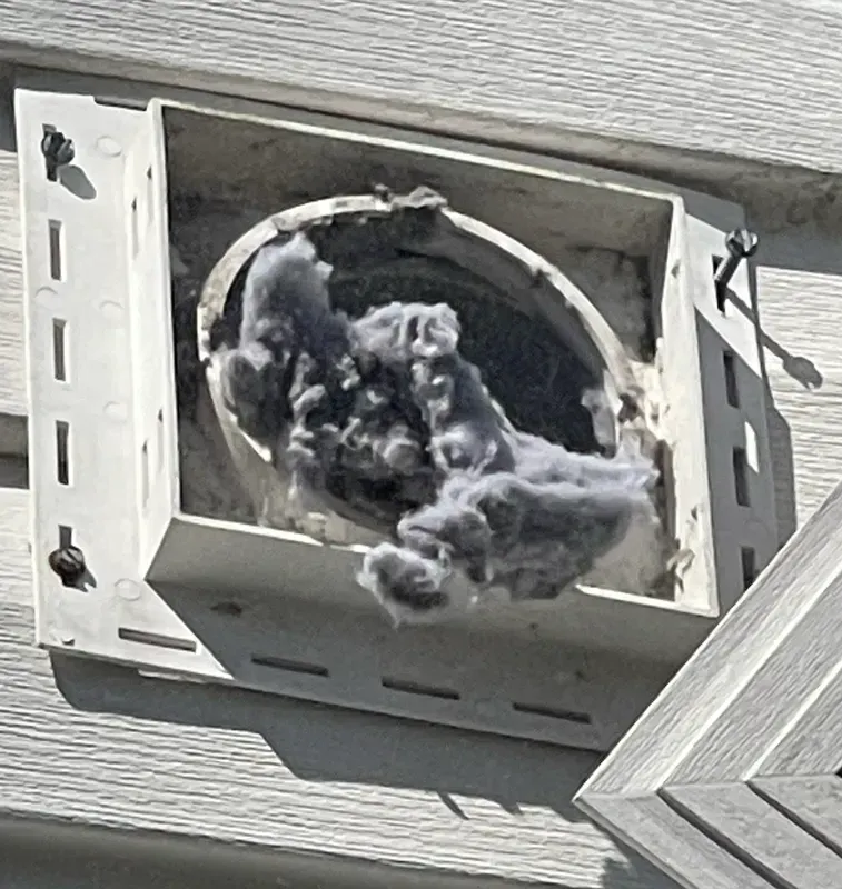 Roof vent with black and gray lint or debris packed inside the opening
