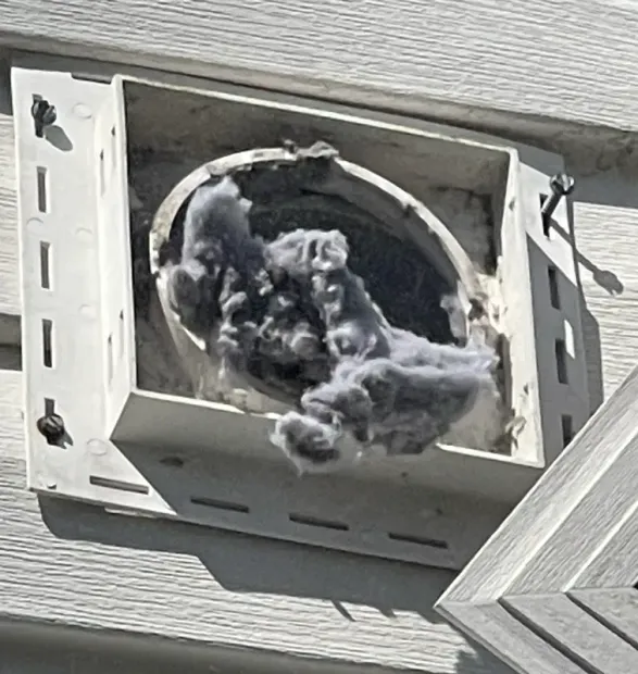 Roof vent with black and gray lint or debris packed inside the opening