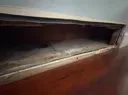 Open wooden drawer with a dark, empty interior and reddish-brown finish