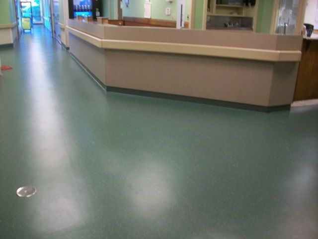 A hospital hallway with a green floor and a counter