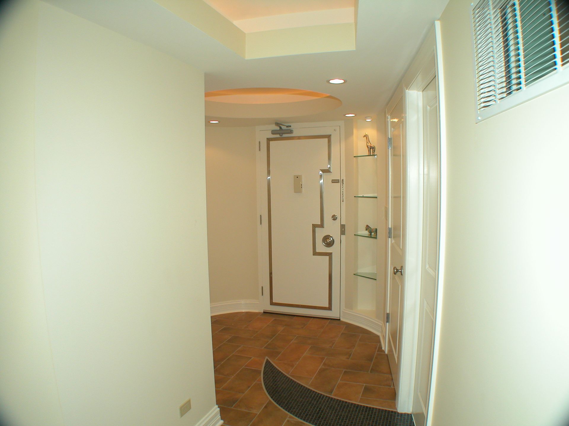 A hallway with a door and shelves on the wall