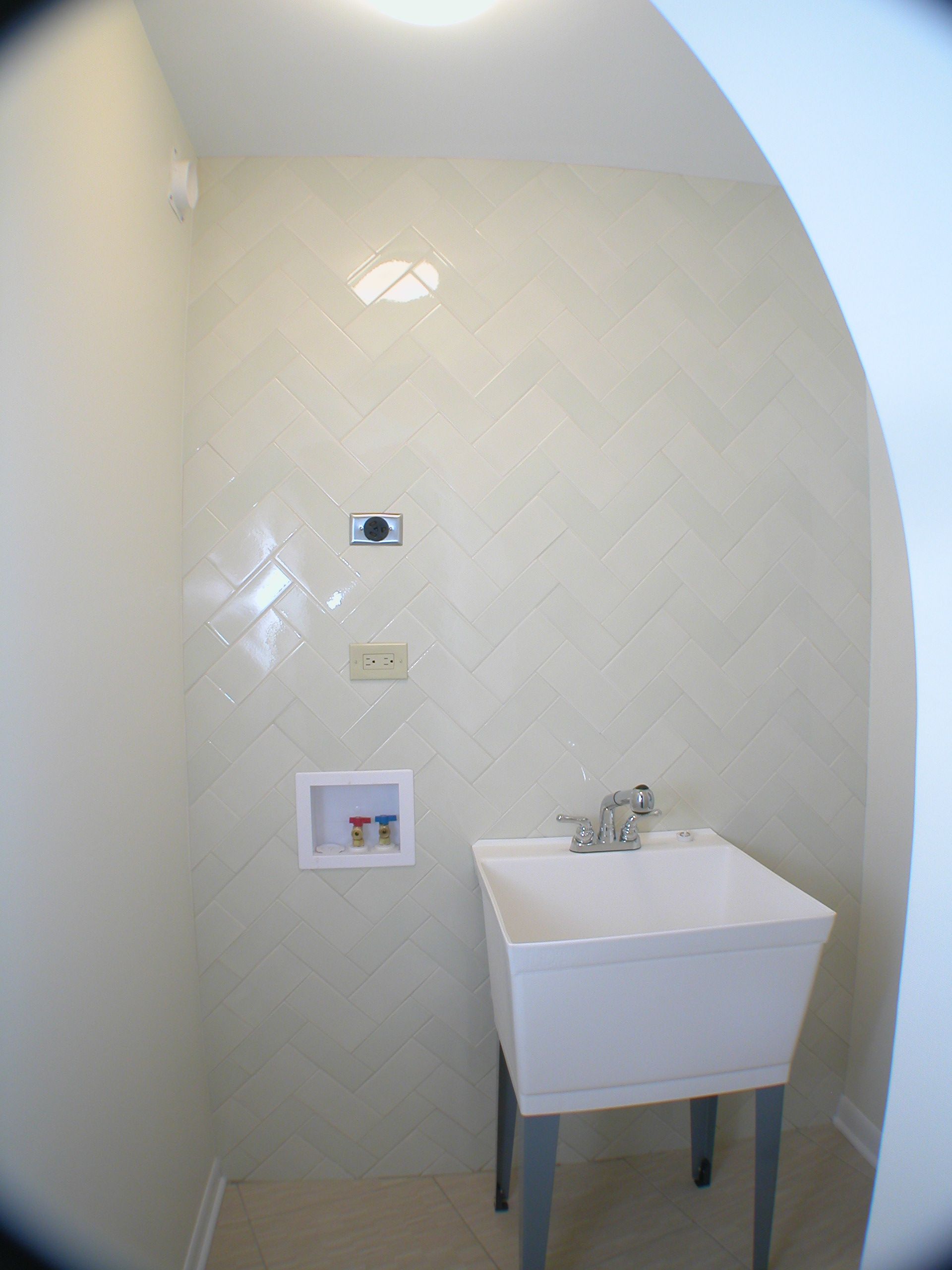 A laundry room with a white sink and a faucet.