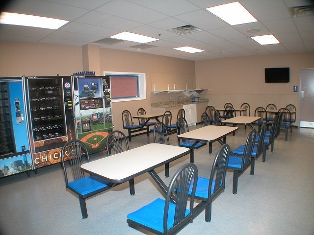 A room with tables and chairs and a vending machine that says chick-fil-a