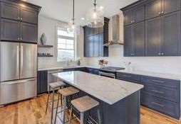 A kitchen with gray cabinets , stainless steel appliances , and a large island.