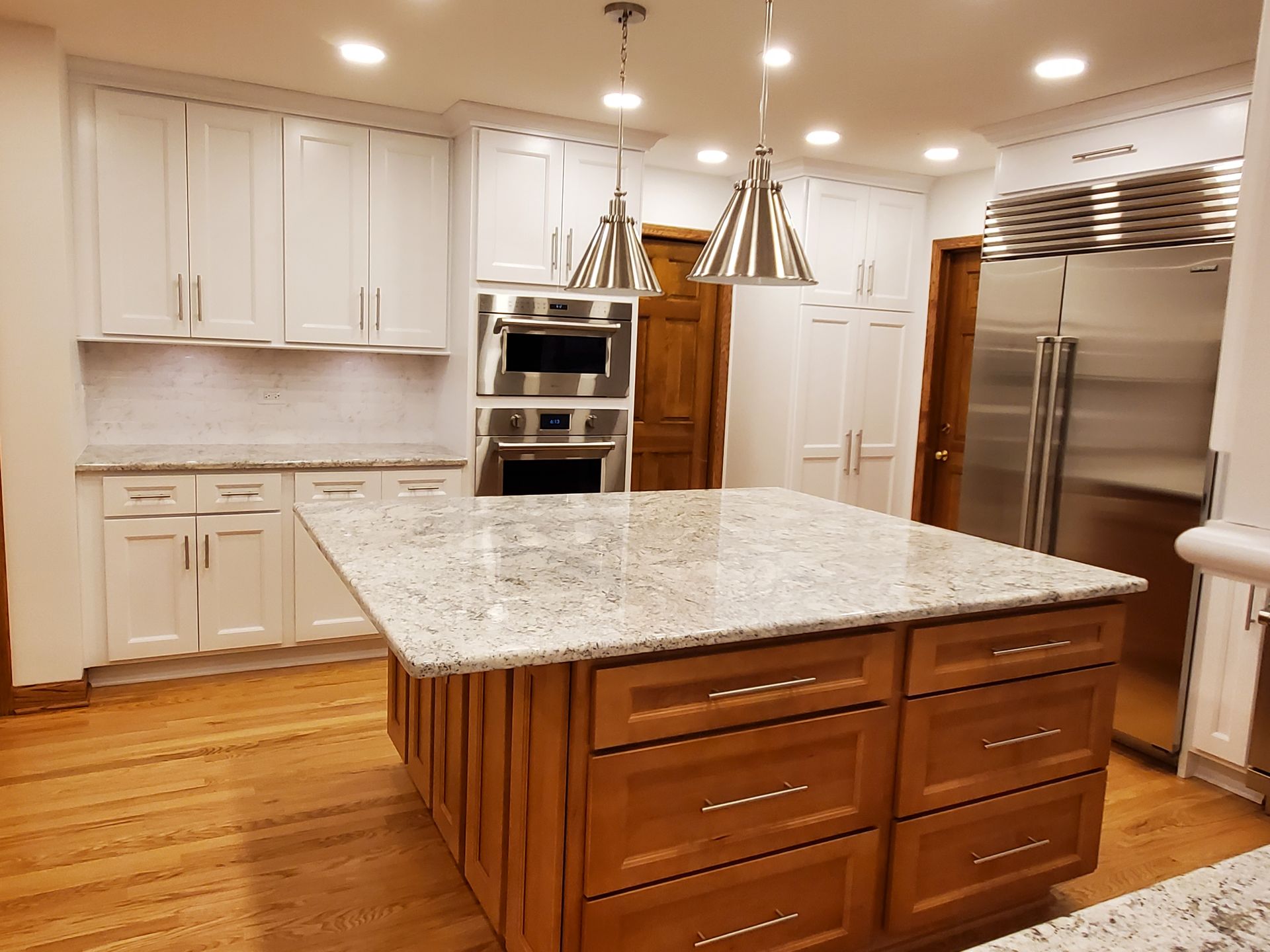 A kitchen with a large island in the middle and stainless steel appliances