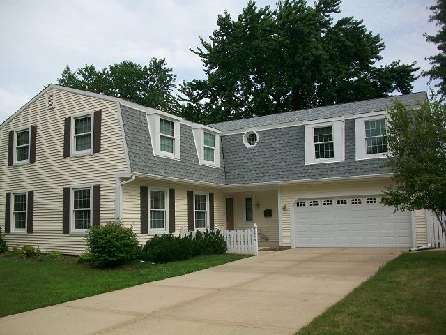 A white house with a gray roof and a white garage door
