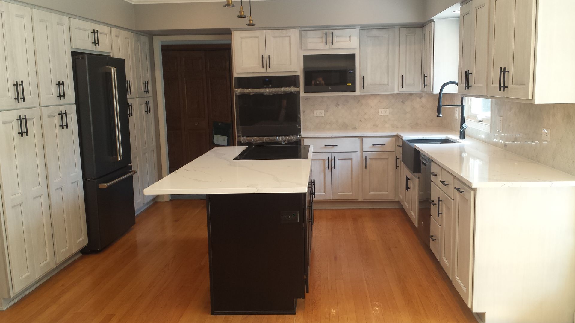 A kitchen with white cabinets , black appliances , and a large island.