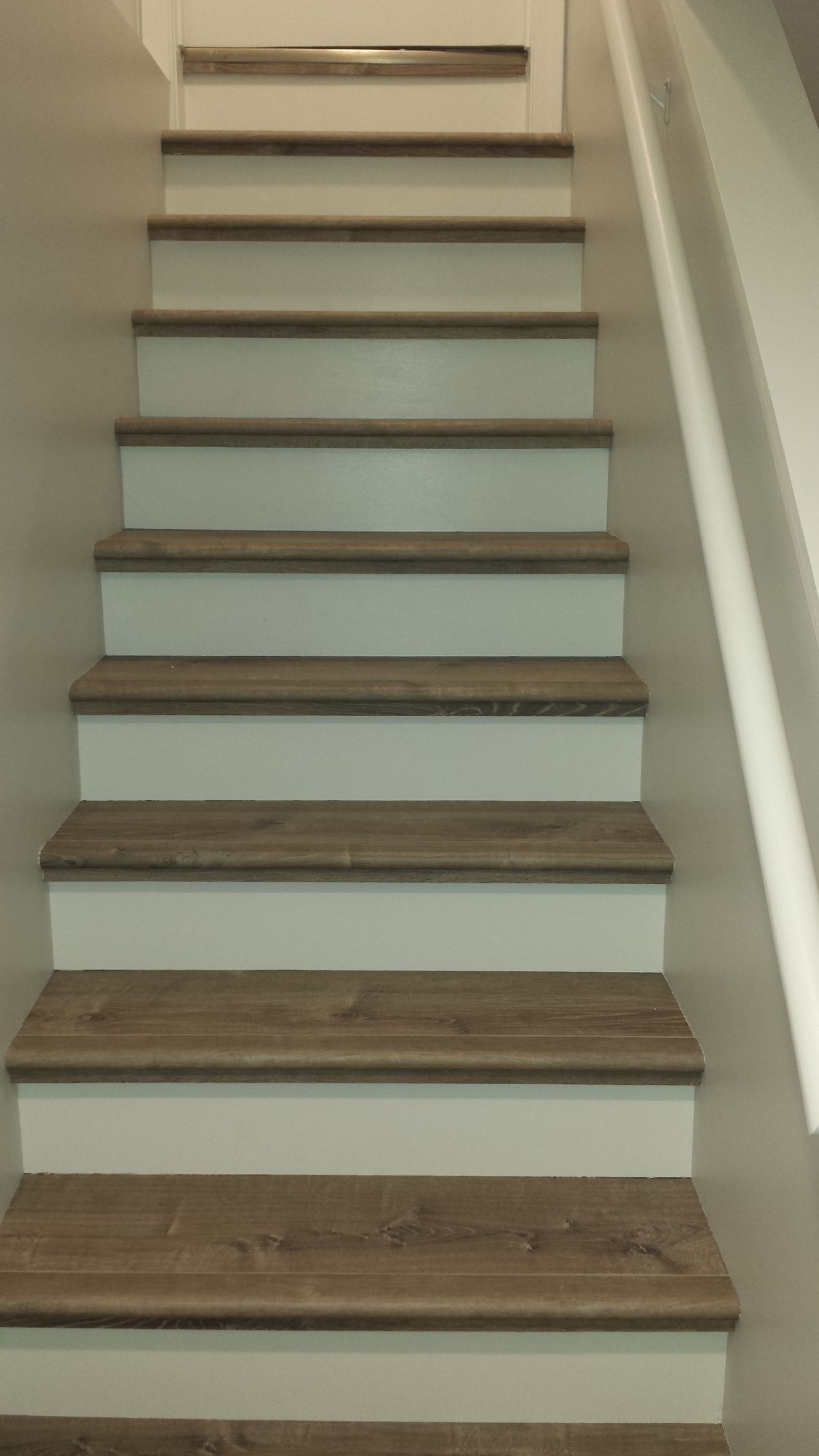 A staircase with white steps and wooden steps in a house.