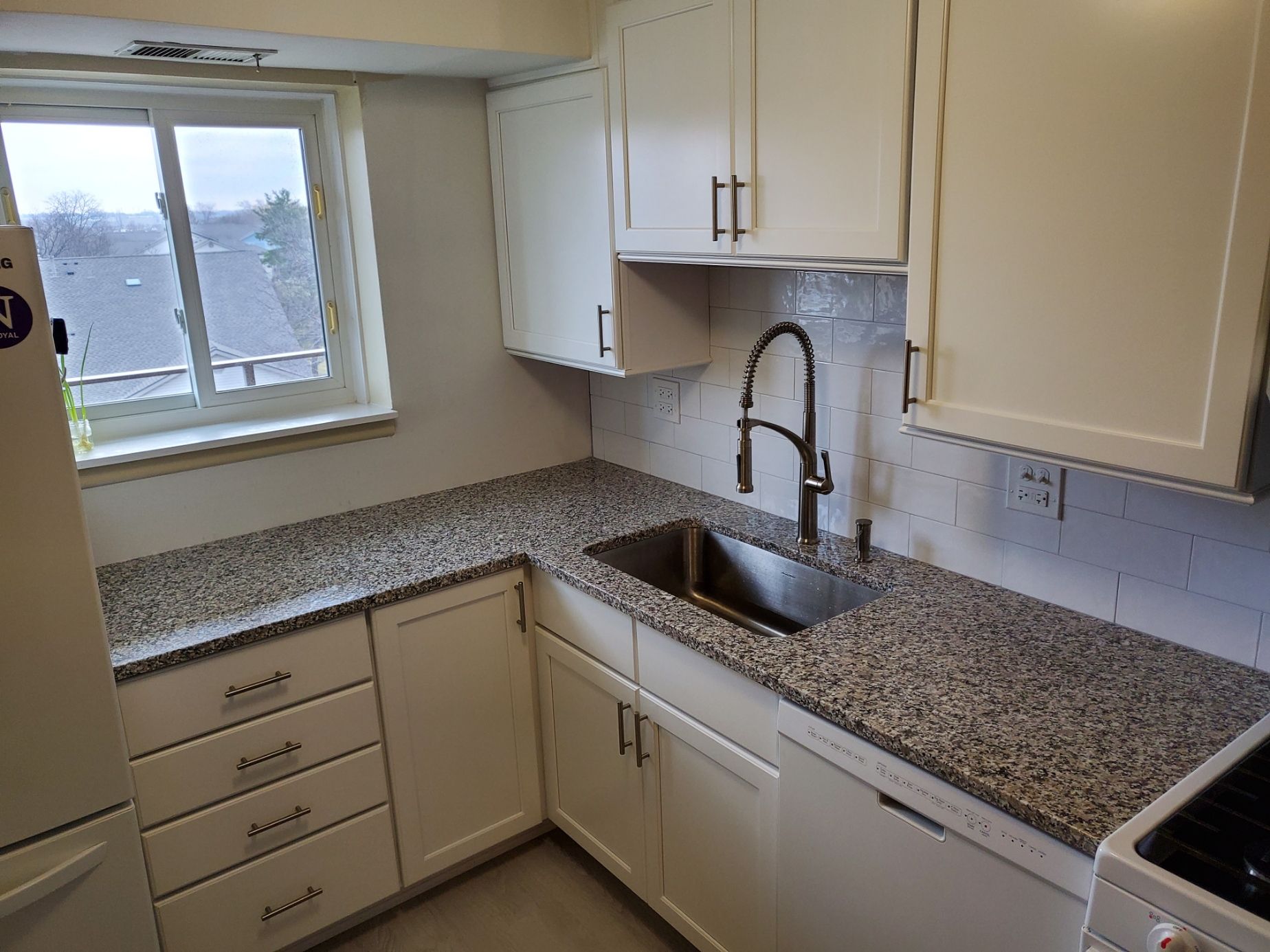 A kitchen with granite counter tops and white cabinets