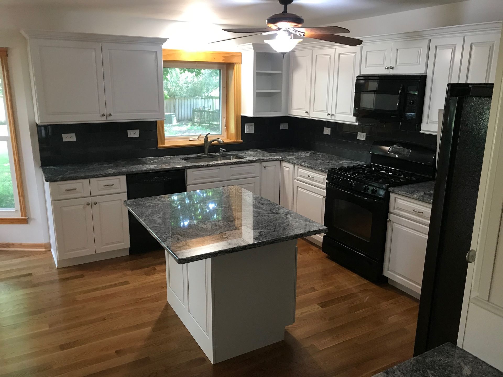 A kitchen with white cabinets and granite counter tops