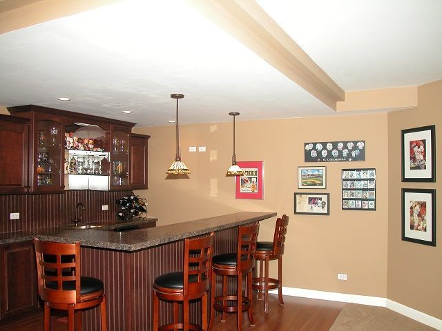 A kitchen with a bar and stools and pictures on the wall