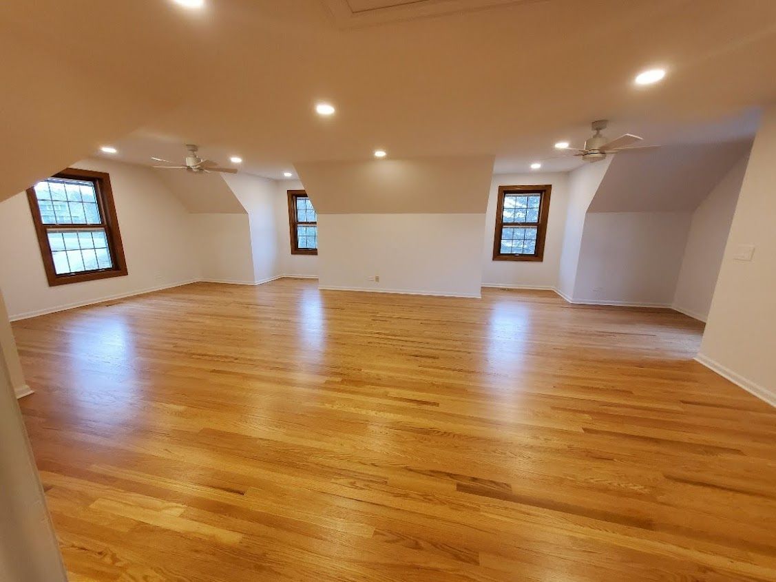 A large empty room with hardwood floors and white walls.