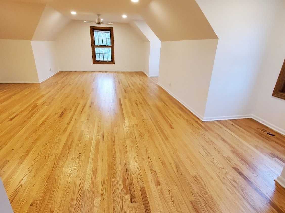 An empty room with hardwood floors and a window