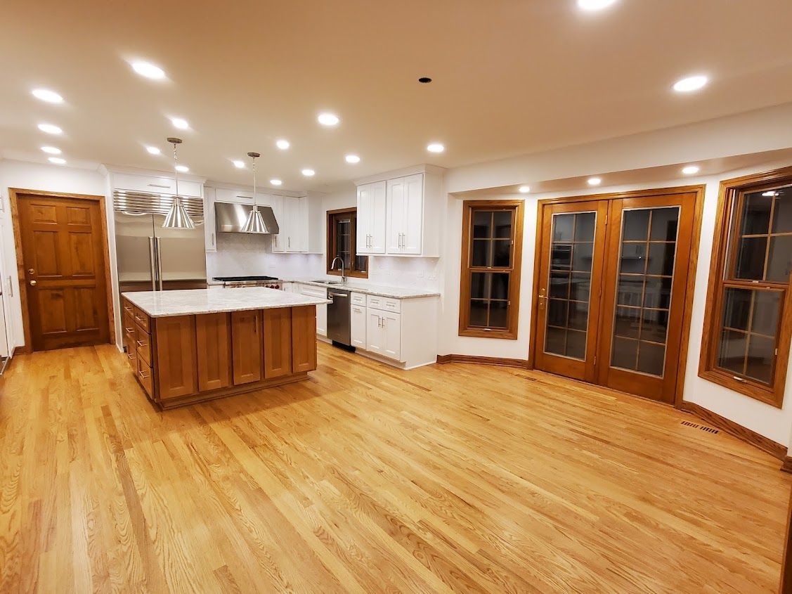 A large empty kitchen with hardwood floors and stainless steel appliances.