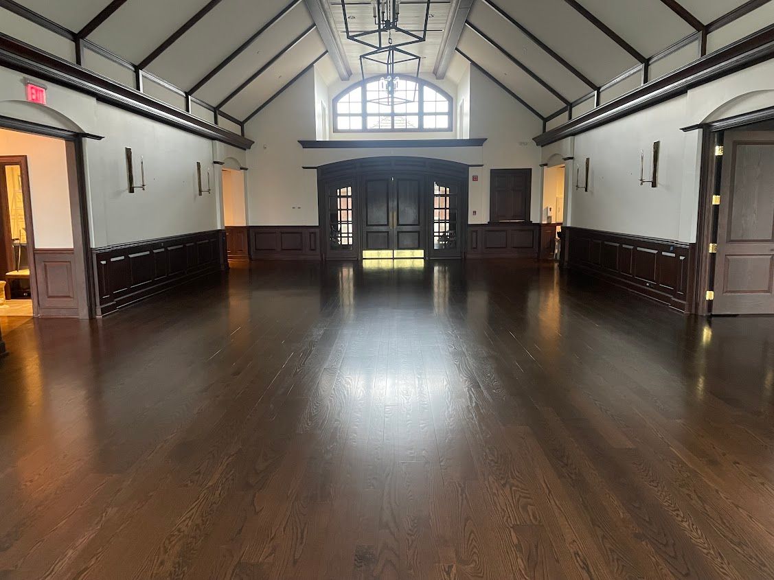 A large empty room with a wooden floor and white walls.