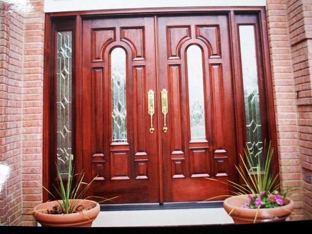 Two potted plants are in front of a wooden door