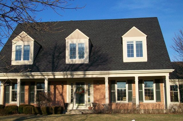 A large brick house with a black roof and white trim