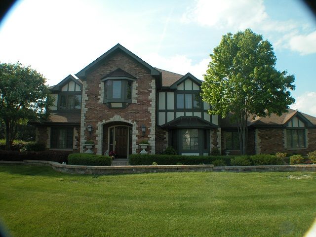 A large brick house with a large lawn in front of it