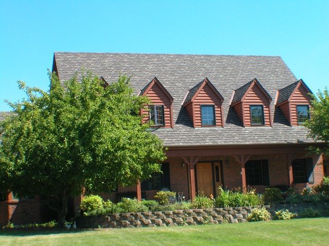 A large brick house with a roof that has shingles on it