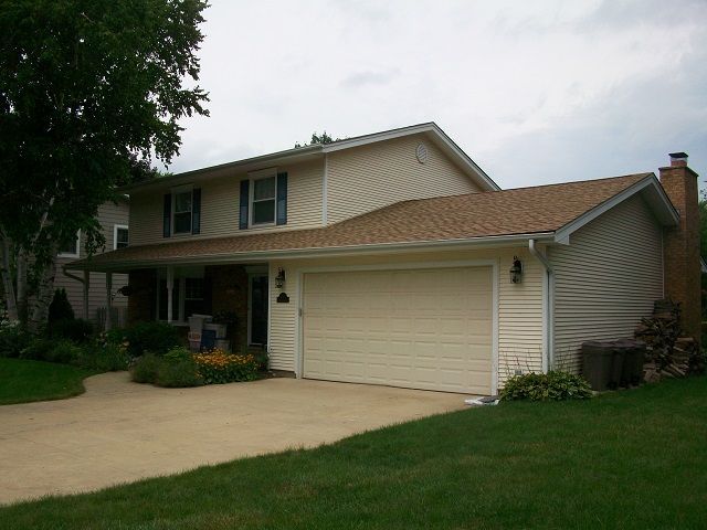 A white house with a brown roof and a white garage door