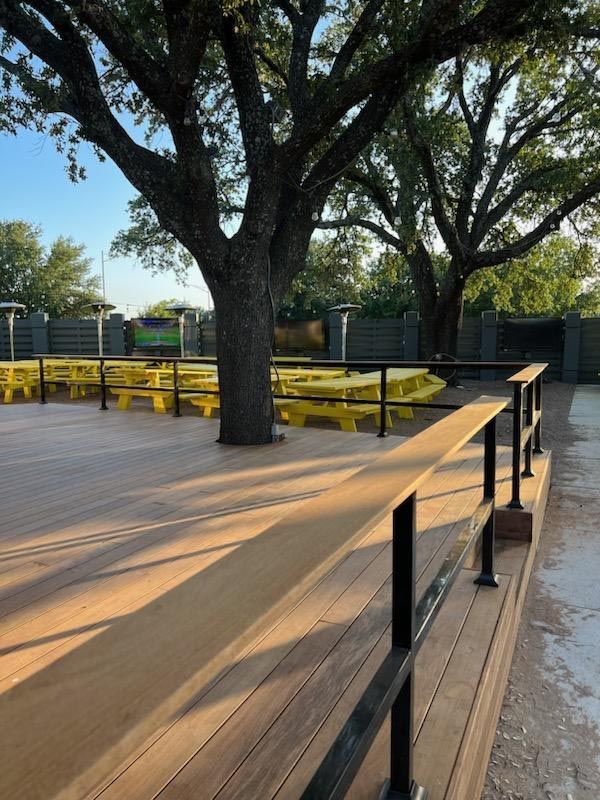 A Wooden Deck With Yellow Picnic Tables and a Tree in the Background