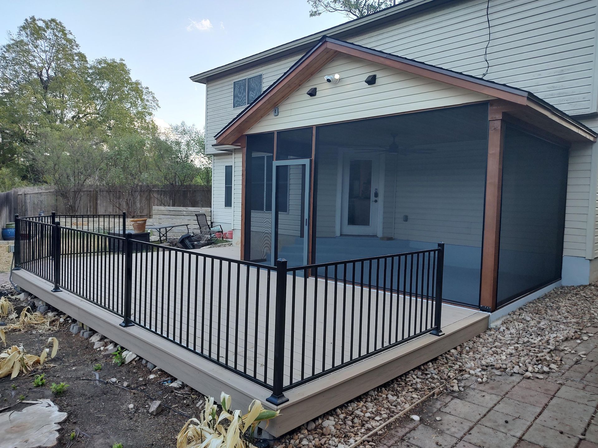 A Screened in Porch With a Fence Around It and a House in the Background
