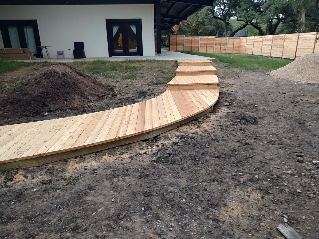 A wooden walkway leading to a house in a backyard.