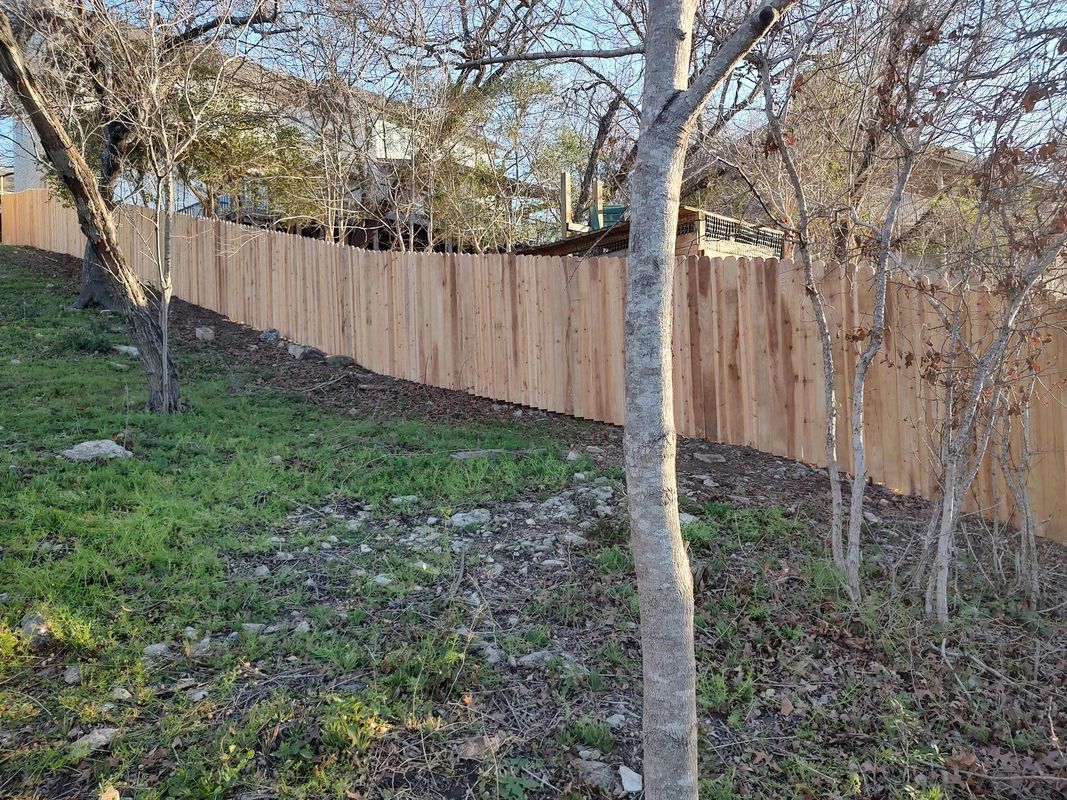 A Wooden Fence is Surrounded by Trees in a Grassy Area
