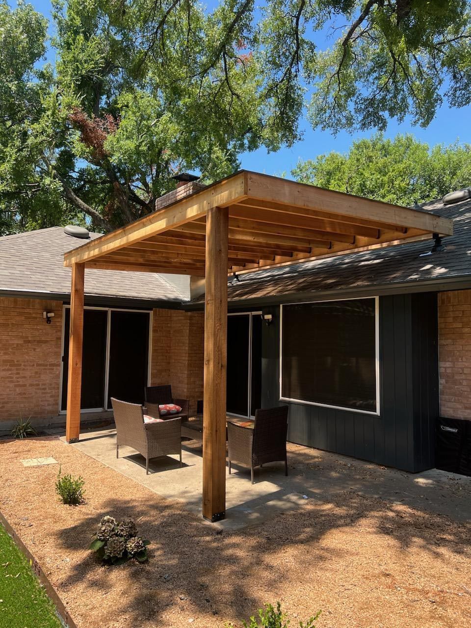 A Patio With a Pergola and Furniture in Front of a House