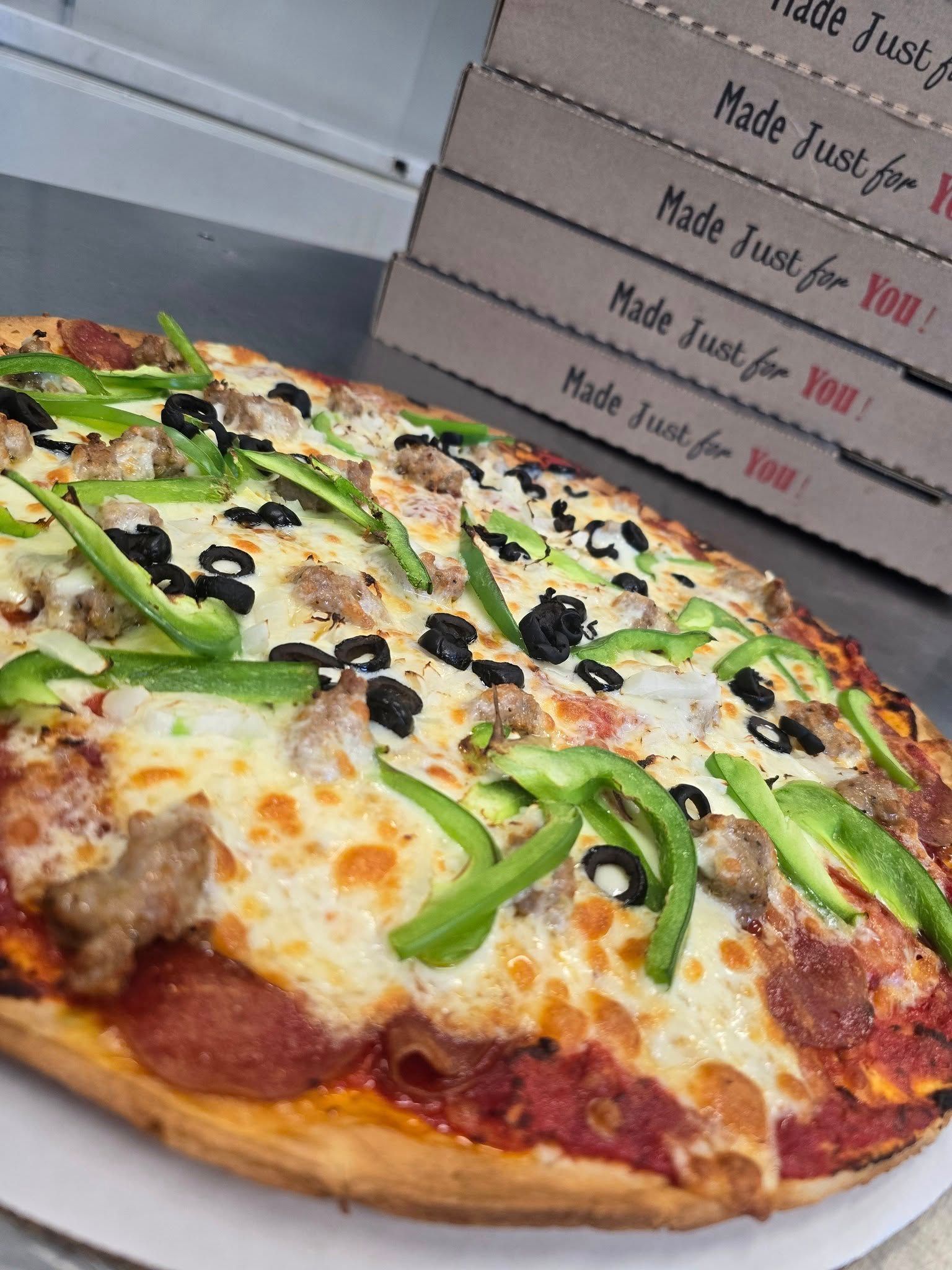 A pizza with pepperoni , cheese , olives and green peppers on a white plate.
