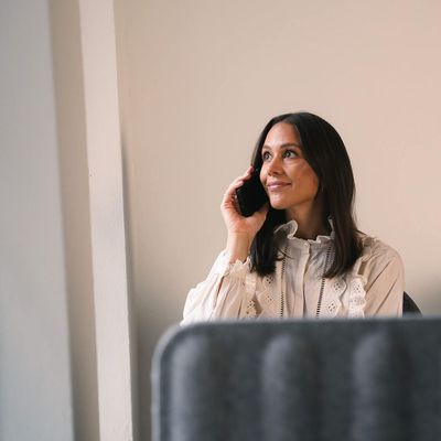 Eine Frau sitzt auf einem Stuhl und telefoniert mit einem Mobiltelefon.