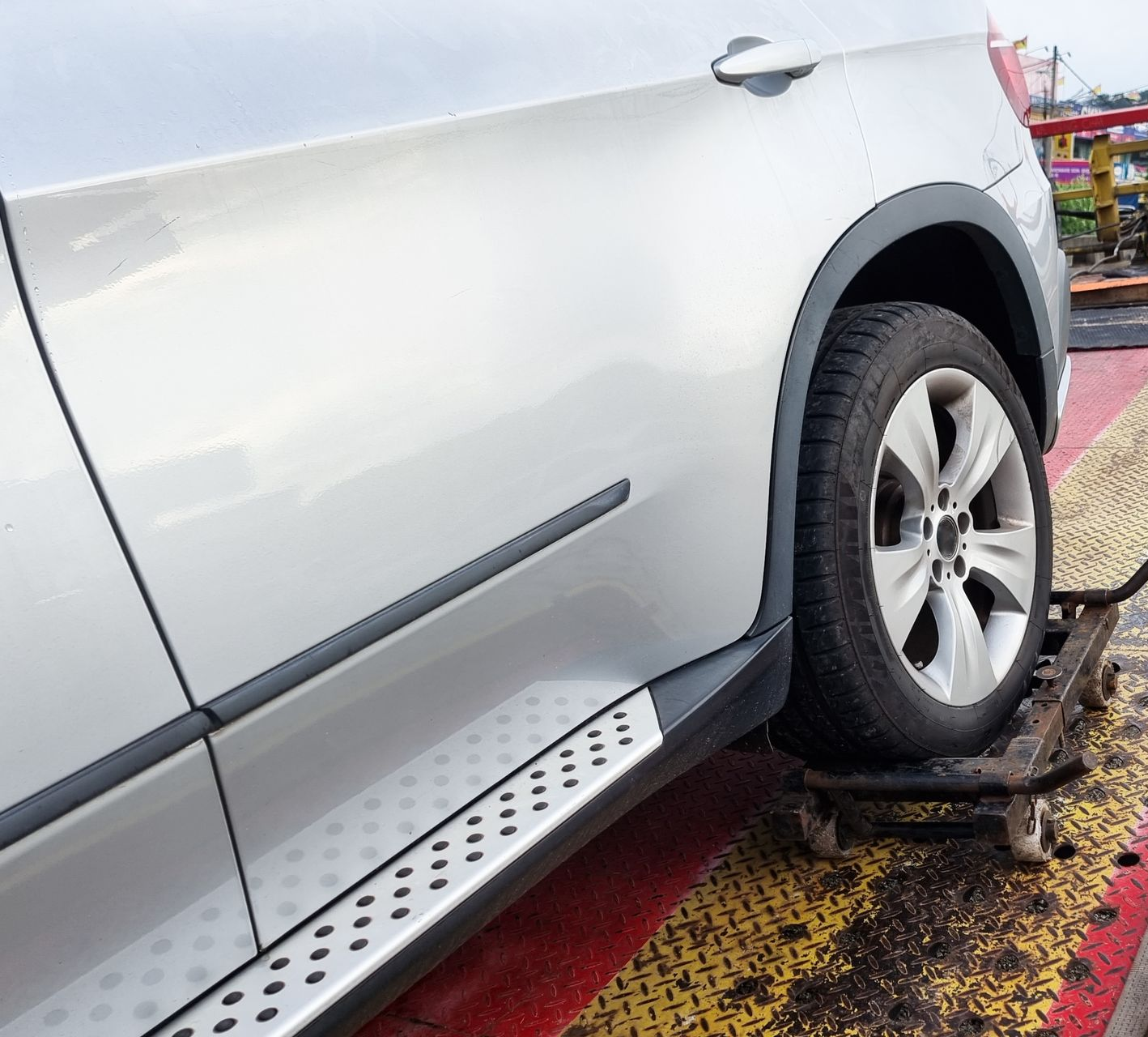 A Silver Suv’s Rear Wheel is Positioned on a Rolling Metal — JP's Towing and Transport in Kingsthorpe, QLD