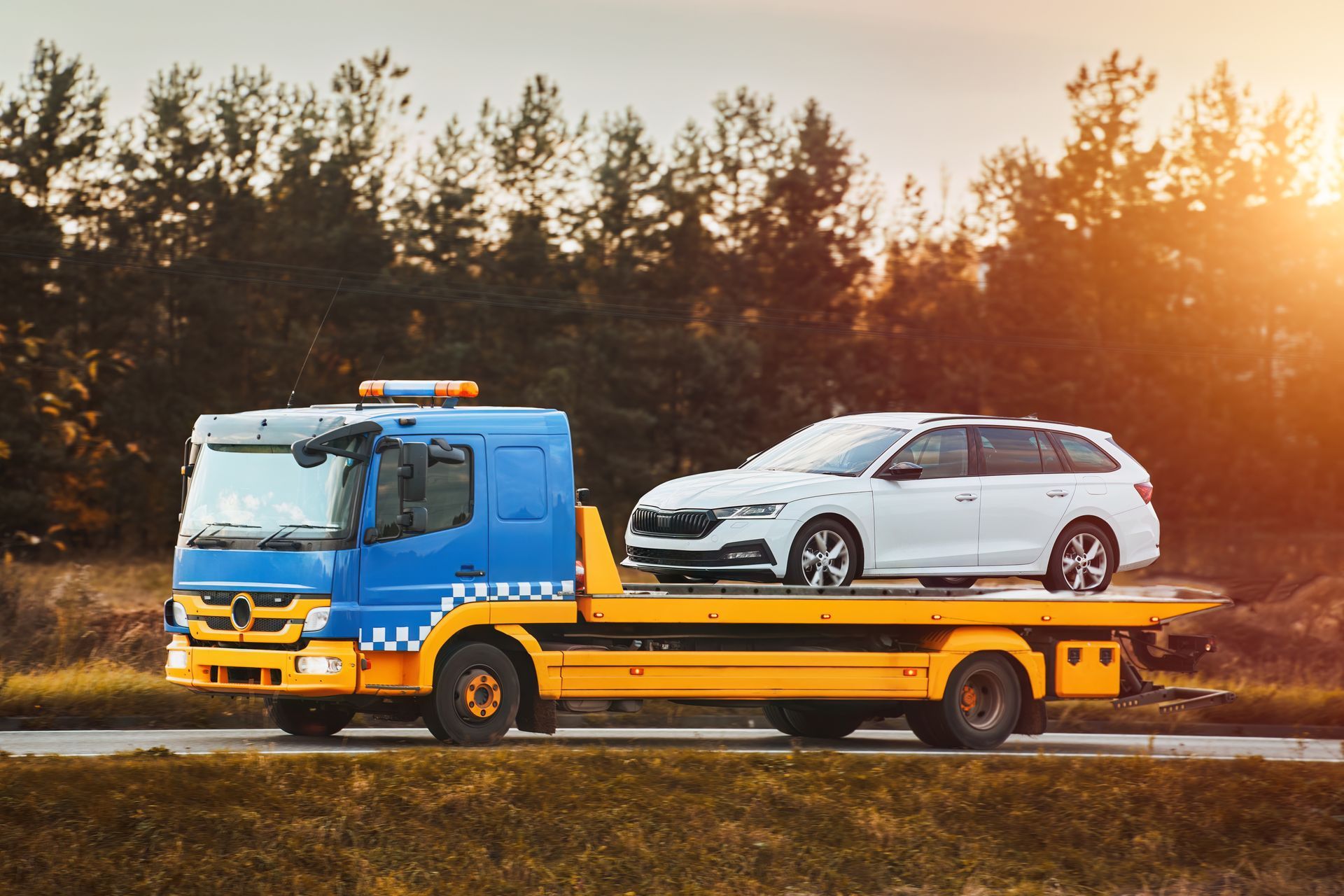 A Blue and Yellow Tow Truck Carries a White Station Wagon — JP's Towing and Transport in Westbrook, QLD