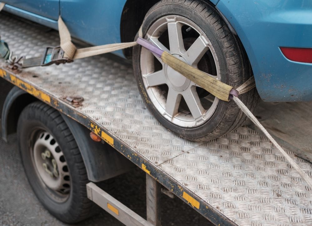 A Blue Car is Secured to the Flatbed of a Tow Truck — JP's Towing and Transport in Gatton, QLD