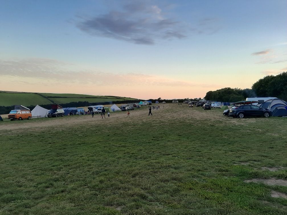 Green grass field at sun set. Dusky sky with tents.