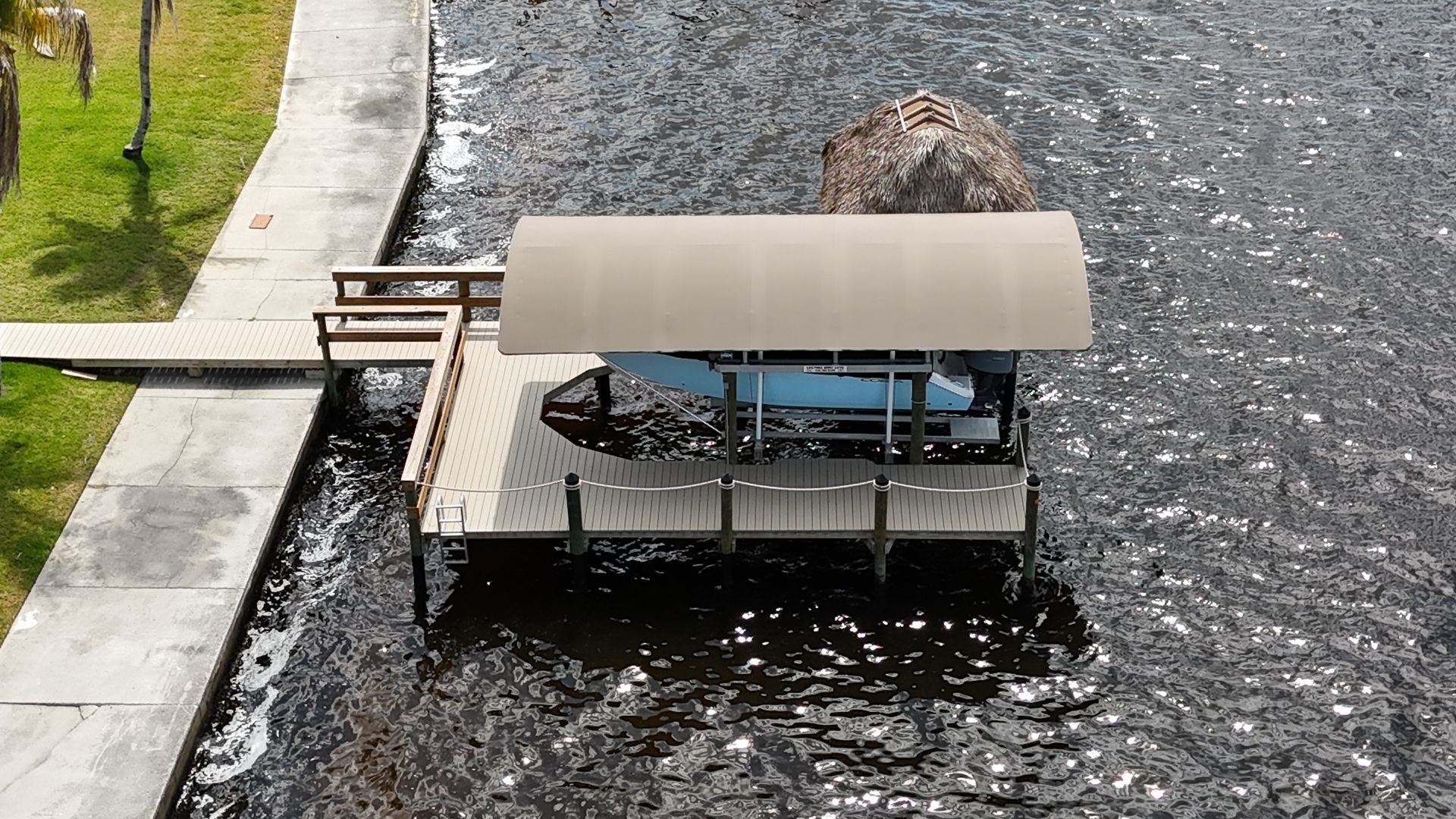Small covered boat docked beside a stone riverbank, floating on dark water.