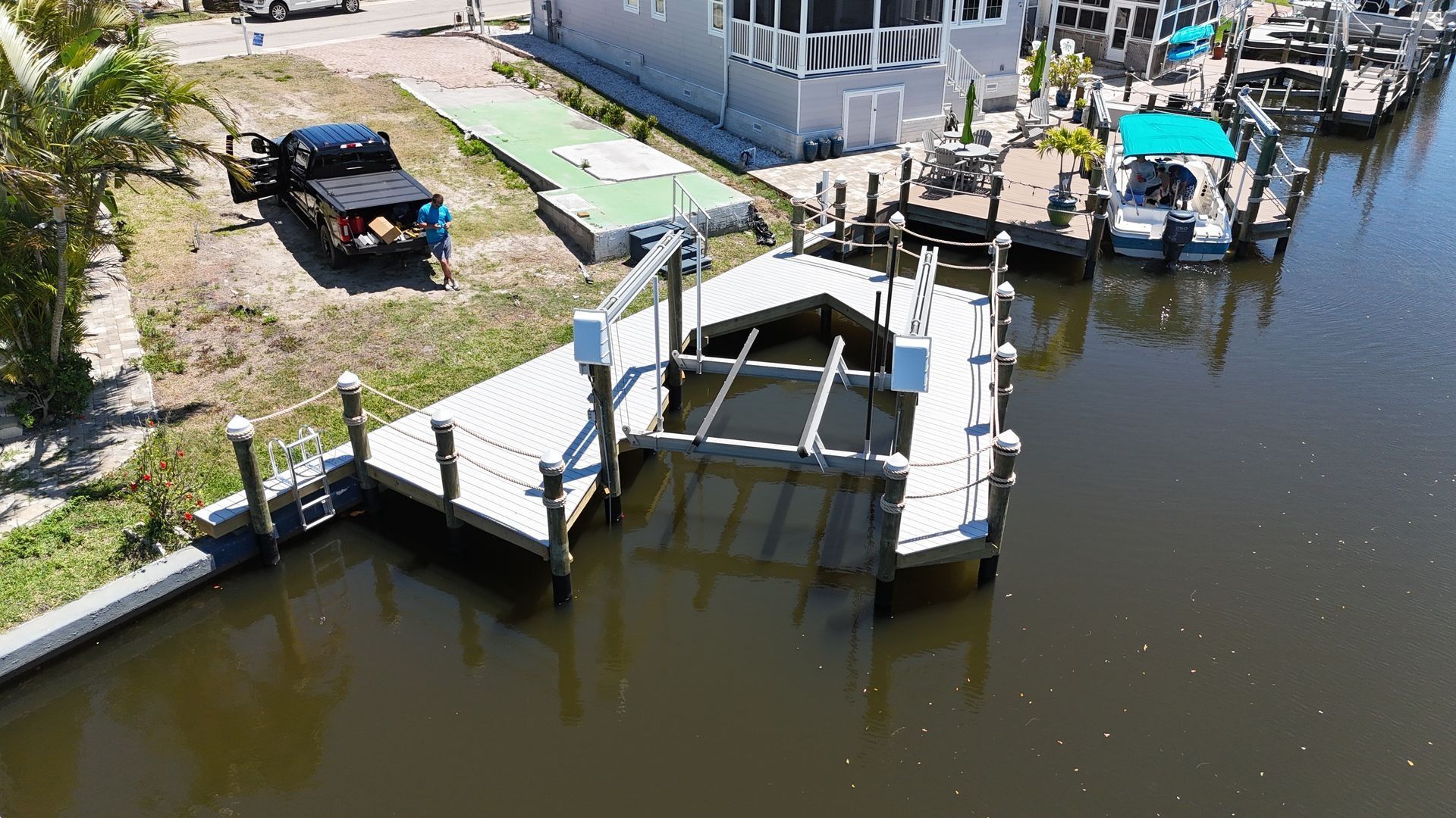 Boathouse and dock on a calm canal beside a parked utility truck and waterfront homes
