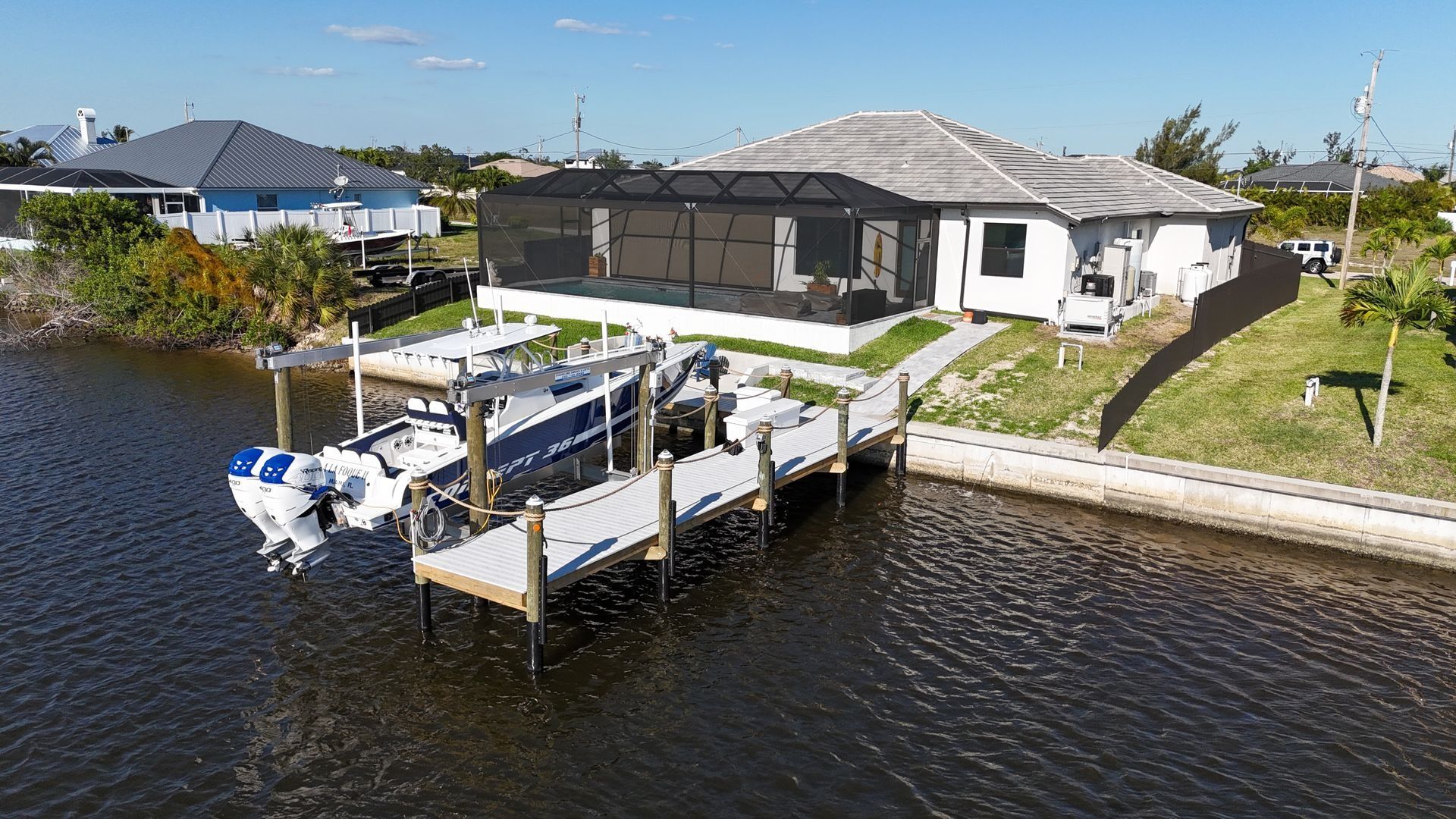 Waterfront house with a dock and boat on a calm canal under a clear sky