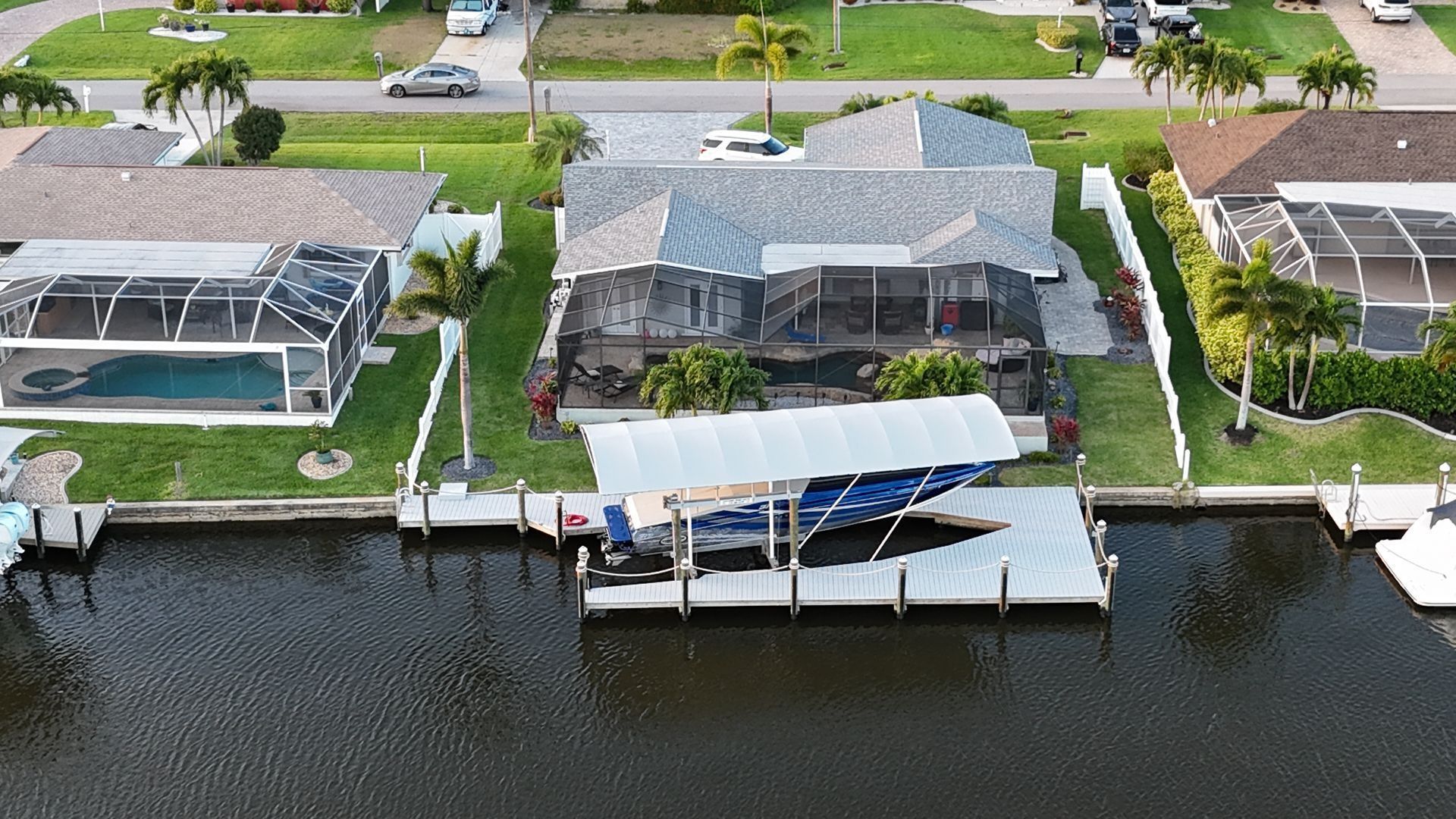 Aerial view of waterfront homes with docks and boat lifts along a canal.