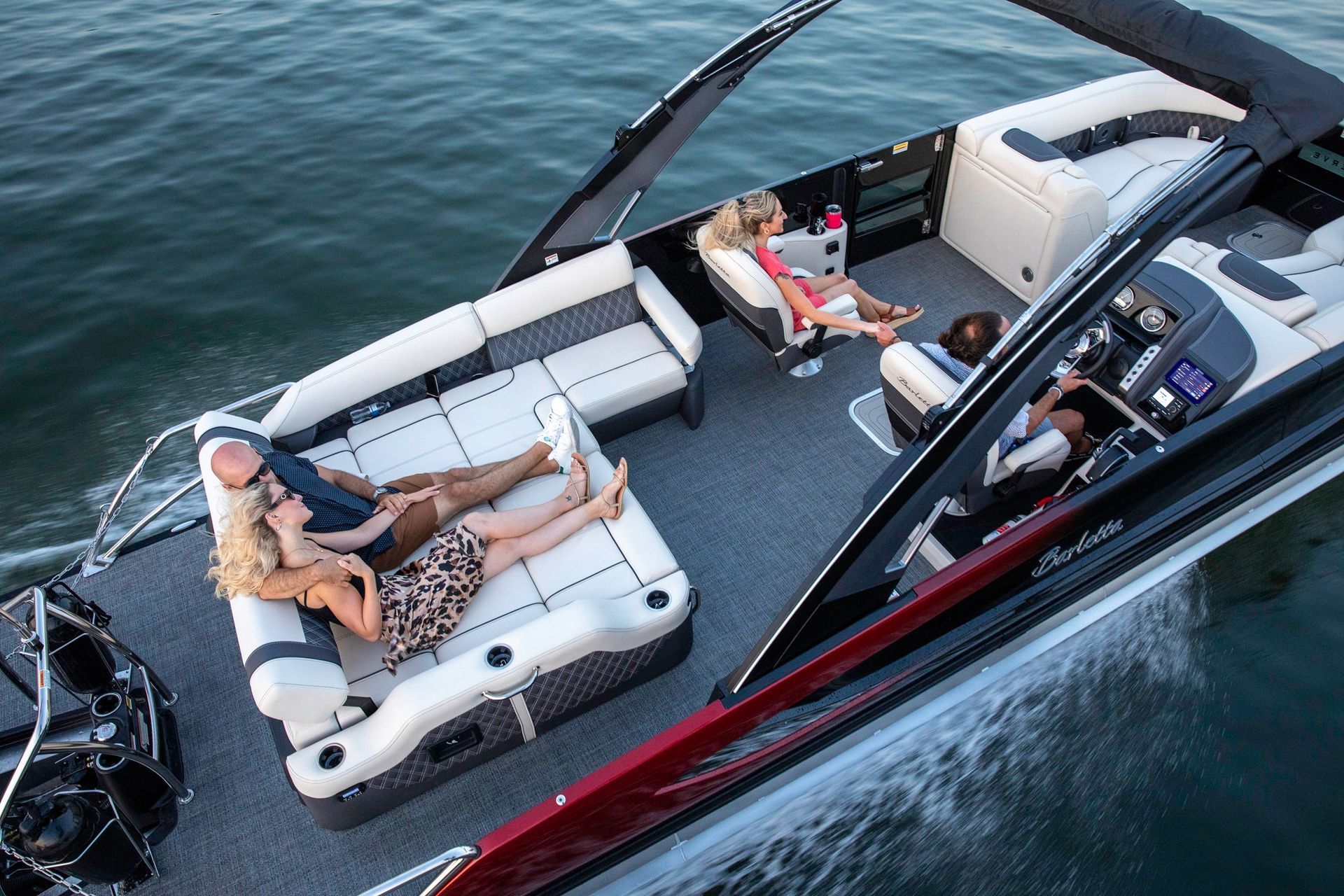 People relaxing on white lounge seats aboard a sleek boat on blue water.