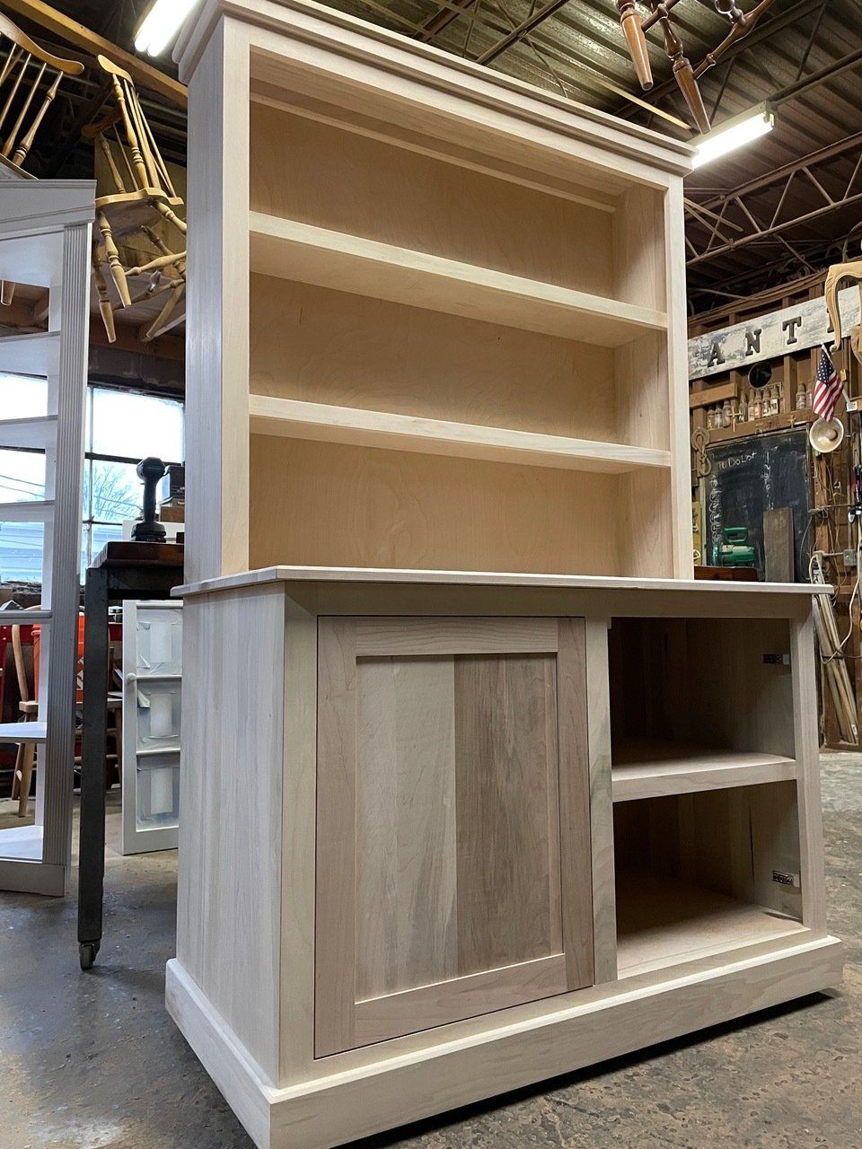 A wooden bookshelf with a cabinet underneath it in a workshop.