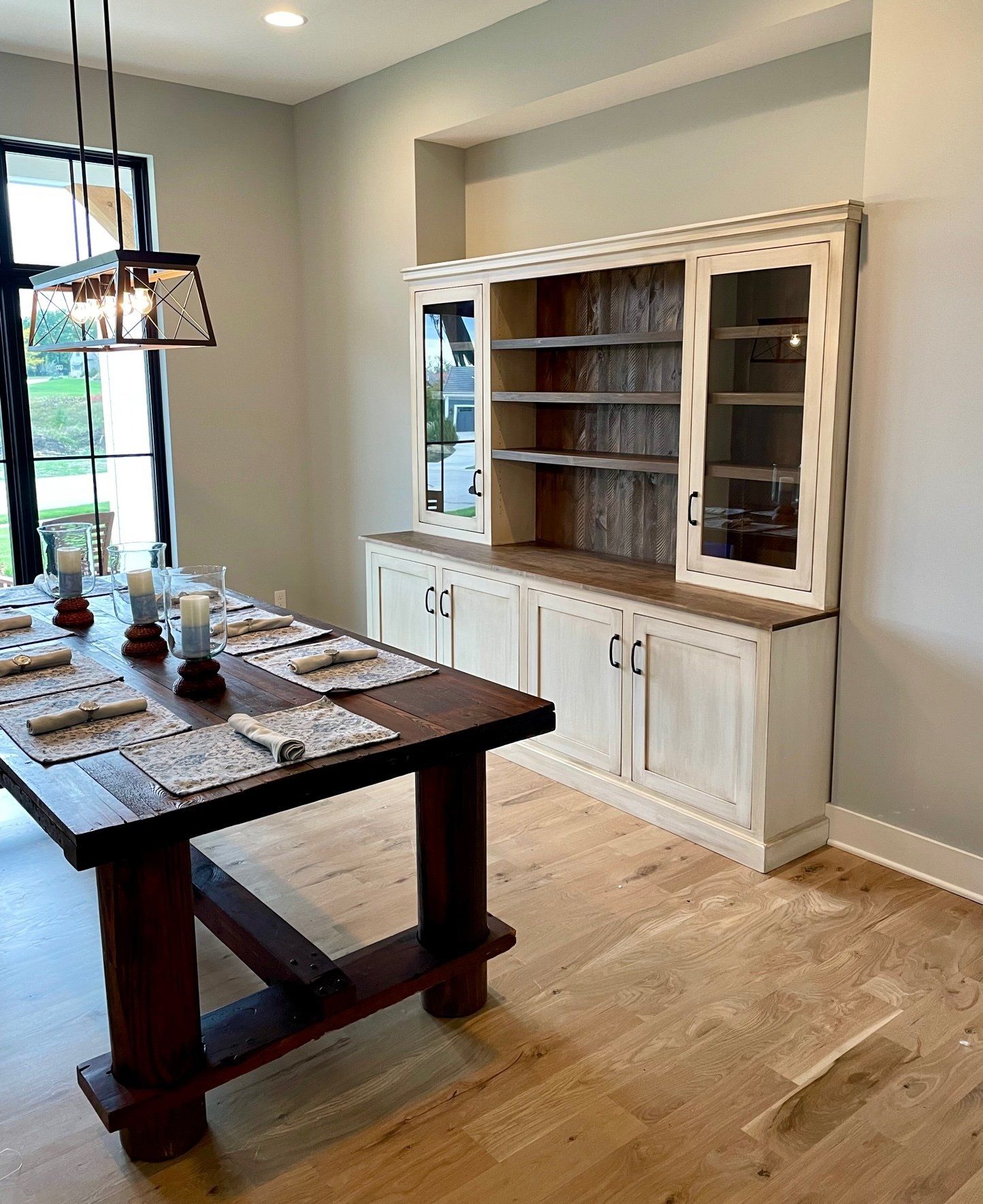 A dining room with a wooden table and white cabinets.