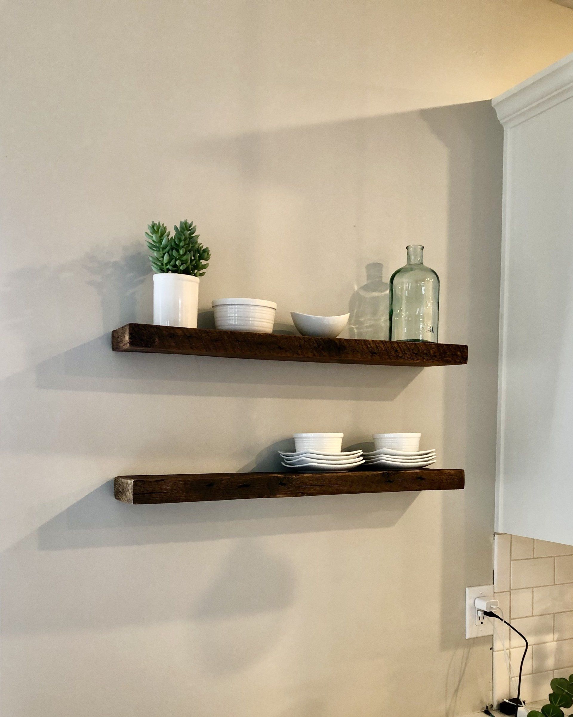 Three wooden shelves are hanging on a wall in a kitchen.