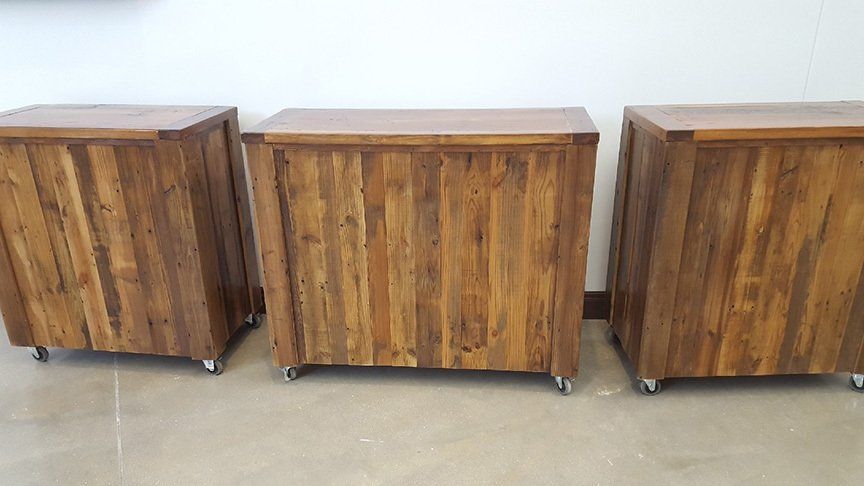 Three wooden boxes with wheels are sitting next to each other on the floor.